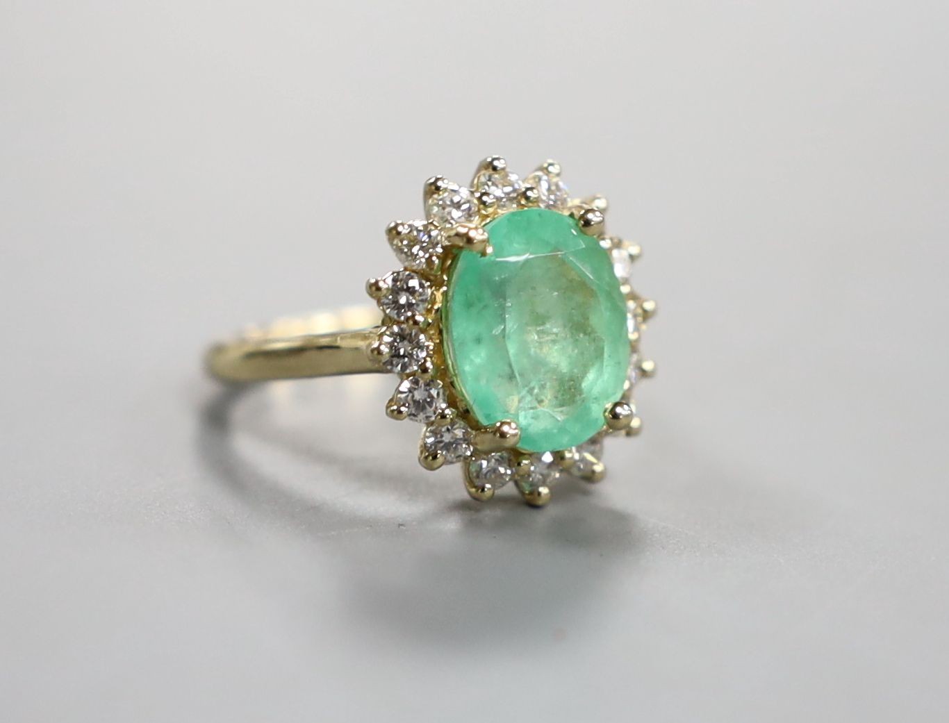 A modern 14k yellow metal, emerald and diamond set oval cluster ring, size M, gross weight 5.9 grams, with accompanying G.A.S. certificate dated 6/7/2016 estimating the emerald to weigh approximately 4.67ct.